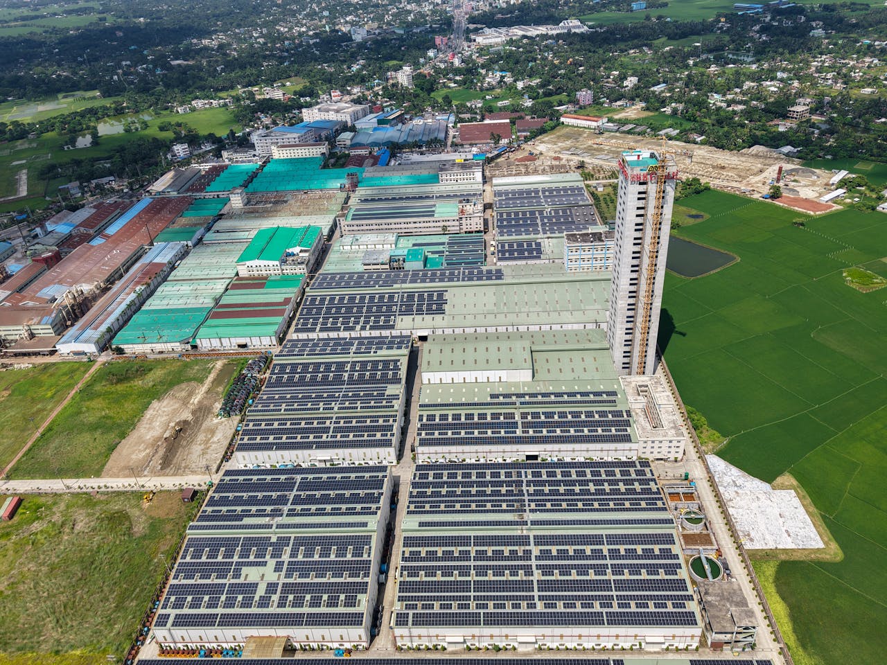 services-01 Sprawling industrial complex with solar panels and green fields, seen from above.